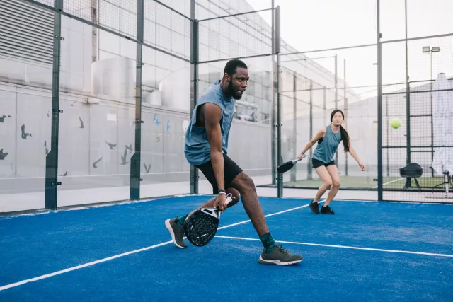 Freunde, die Paddle-Tennis auf dem blauen Außenplatz spielen