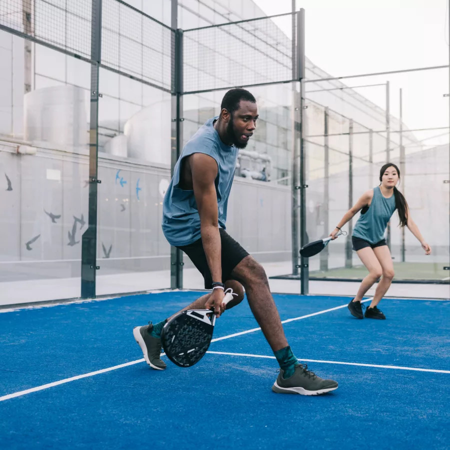 Freunde, die Paddle-Tennis auf dem blauen Außenplatz spielen