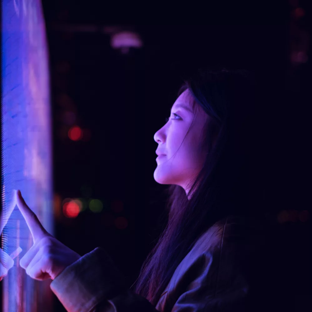 Entdecken Sie die faszinierende Welt der interaktiven Technologie! Dieses Bild zeigt eine Person, die einen hochmodernen Touchscreen in einer dunklen, stimmungsvollen Umgebung bedient. Die leuchtenden Farben und das futuristische Design machen es zu einem perfekten Beispiel für die Verschmelzung von Mensch und Technologie.