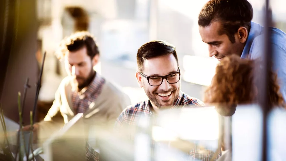 Vier Personen in einem Büro, die zusammenarbeiten und lachen