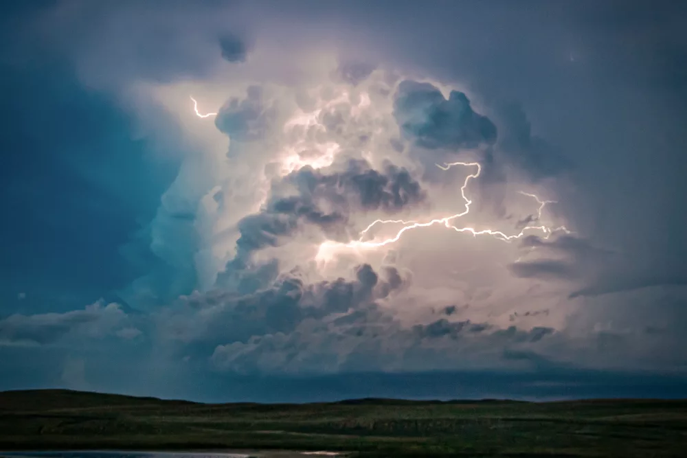 Auf dem Foto ist eine graue Wolke zu sehen, die von innen heraus durch einen strahlenden Blitz leuchtet.