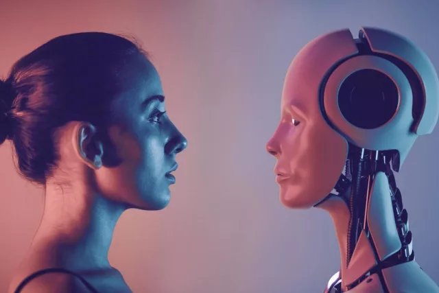 Eine Frau und ein Roboter sind von der Seite zu sehen, wie sie sich frontal ansehen.