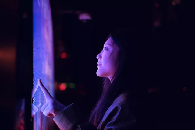Entdecken Sie die faszinierende Welt der interaktiven Technologie! Dieses Bild zeigt eine Person, die einen hochmodernen Touchscreen in einer dunklen, stimmungsvollen Umgebung bedient. Die leuchtenden Farben und das futuristische Design machen es zu einem perfekten Beispiel für die Verschmelzung von Mensch und Technologie.