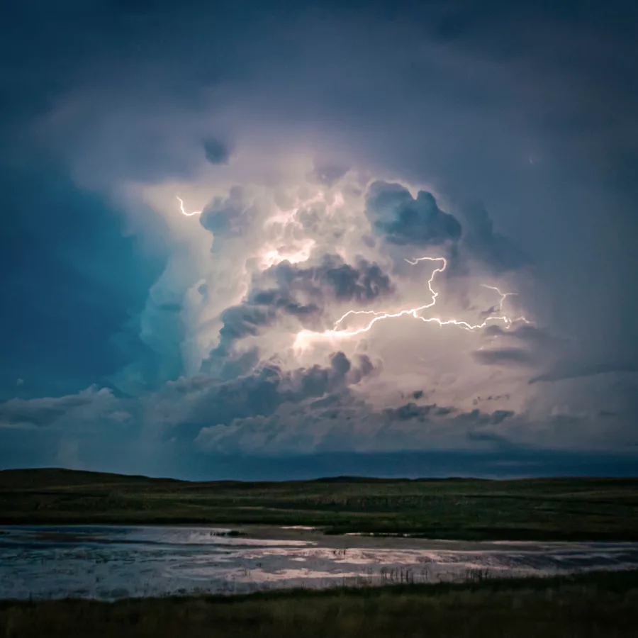 Auf dem Foto ist eine graue Wolke zu sehen, die von innen heraus durch einen strahlenden Blitz leuchtet.